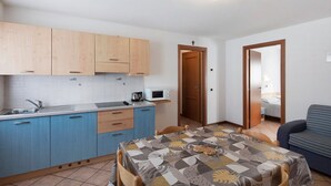 Una cocina compacta con armarios azules, un microondas y un lavabo.