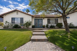 A single-story house with a front door, a small porch, and a well-maintained lawn.