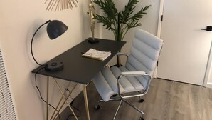 Ein moderner Schreibtisch mit Lampe, Notizblock und Pflanze.