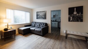 Ein modernes Wohnzimmer mit Ecksofa, einer Bank, einer Lampe und Kunstwerken an den Wänden.