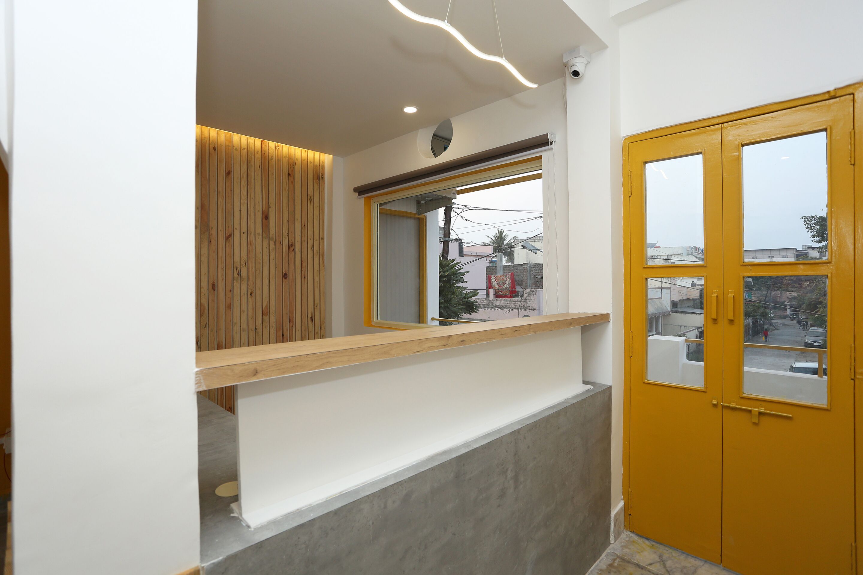 Un intérieur moderne avec un mur lambrissé en bois, un comptoir blanc et une porte jaune.