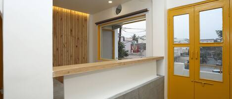 A modern interior with a wooden panel wall, a white counter, and a yellow door.