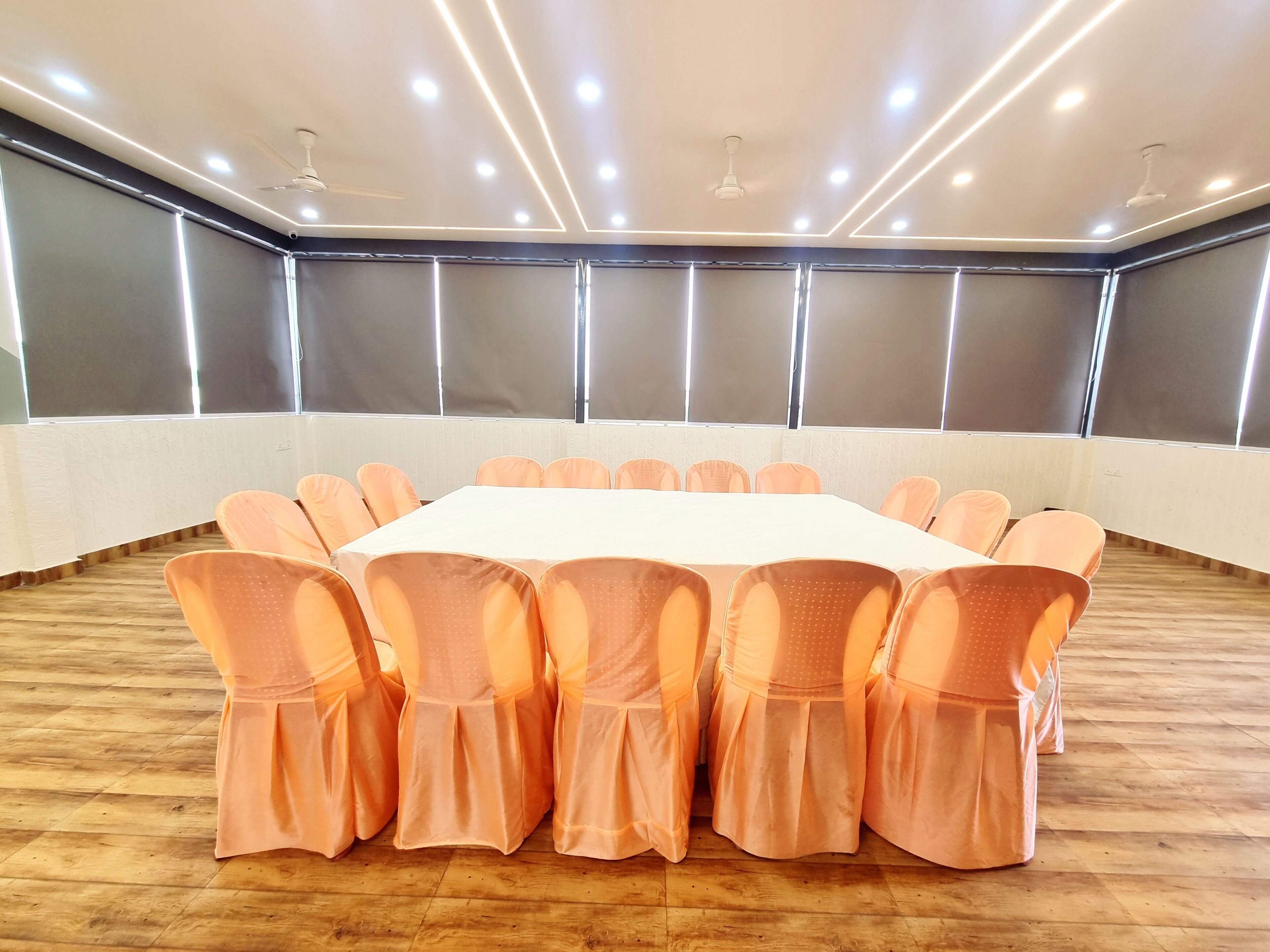 A conference room with a long table, orange chairs, and ceiling lights.