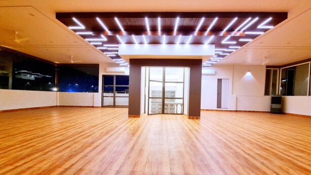 A spacious room with wooden flooring, large windows, and a modern ceiling design. - Stay inn nest (Bhopal)