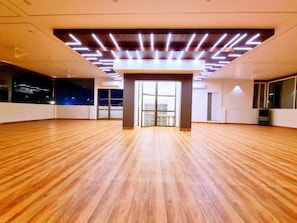 Una habitación amplia con suelo de madera, ventanas grandes y un diseño de techo moderno.