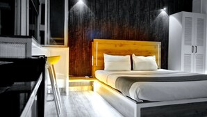 A modern bedroom with a wooden headboard, a bed with white bedding, a bedside table with a lamp, and a wardrobe. - Stay inn nest (Bhopal)