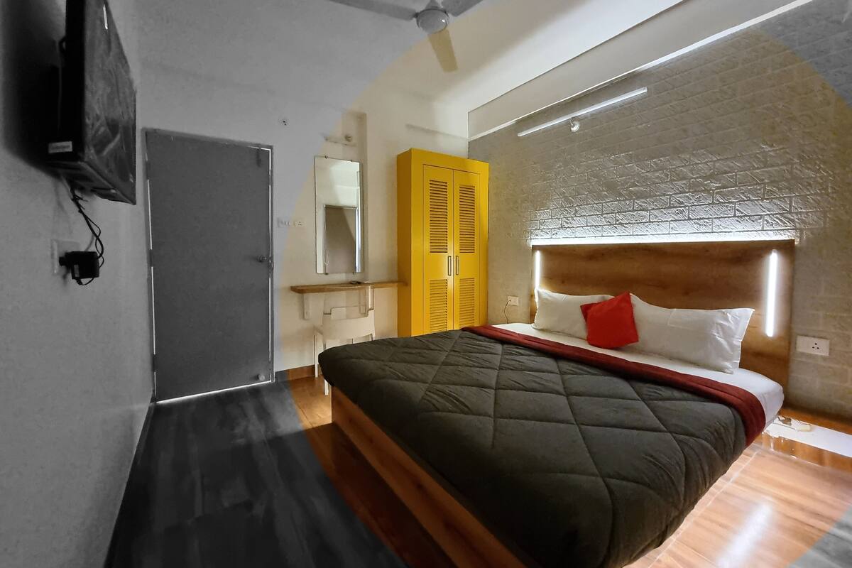 A bedroom with a bed, a ceiling fan, a mirror, and a wardrobe.