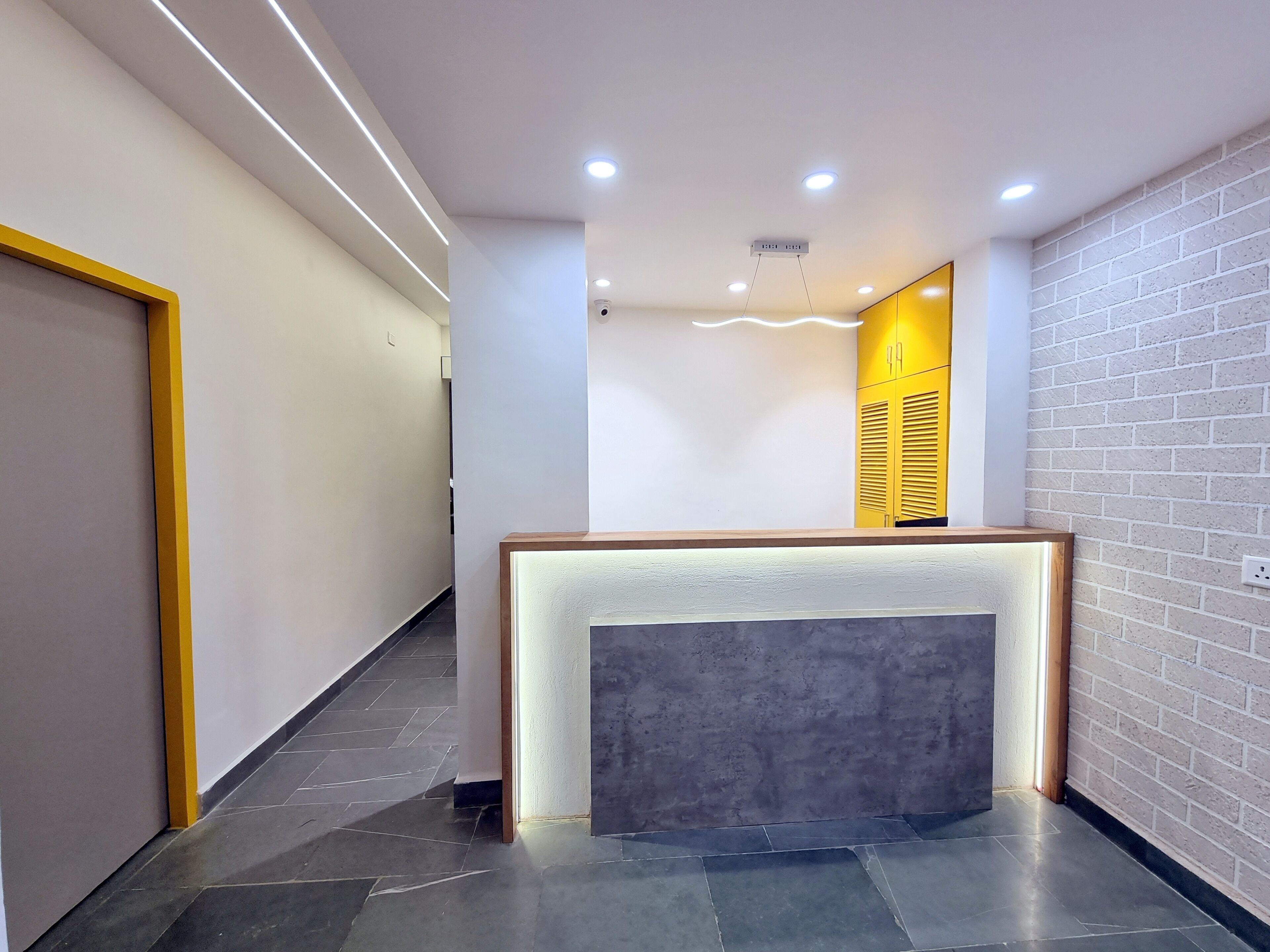 A modern reception area with a reception desk, a digital clock, and a staircase leading to an upper level.