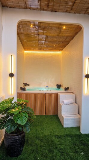 A spa area with a hot tub, wooden steps, and a potted plant. - Stay inn nest (Bhopal)