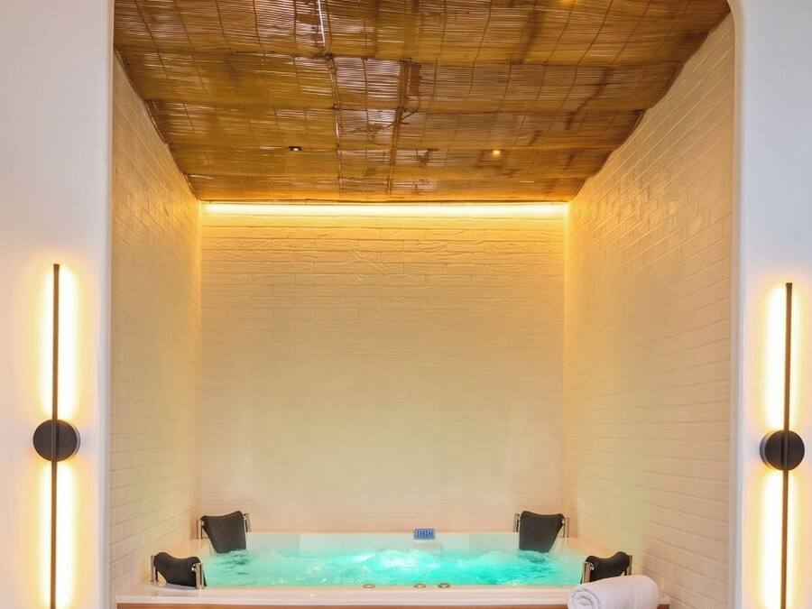 A spa area with a hot tub, wooden steps, and wall-mounted lights.