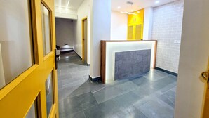 A modern hotel lobby with a reception desk, a staircase, and a brick wall. - Stay inn nest (Bhopal)