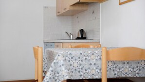 A kitchen with a tiled backsplash, a kettle on the counter, and a table with a floral tablecloth. - Apartment "Bait del Pont 52B" with Mountain View, Wi-Fi & Garden (Trepalle)