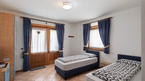 A bedroom with two beds, a wooden door, and a window with curtains. - Apartment "Bait del Pont 52B" with Mountain View, Wi-Fi & Garden (Trepalle)