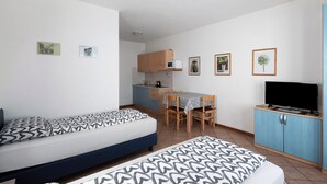 A compact room with a bed, a TV, a kitchenette, and a dining area. - Apartment "Bait del Pont 52B" with Mountain View, Wi-Fi & Garden (Trepalle)