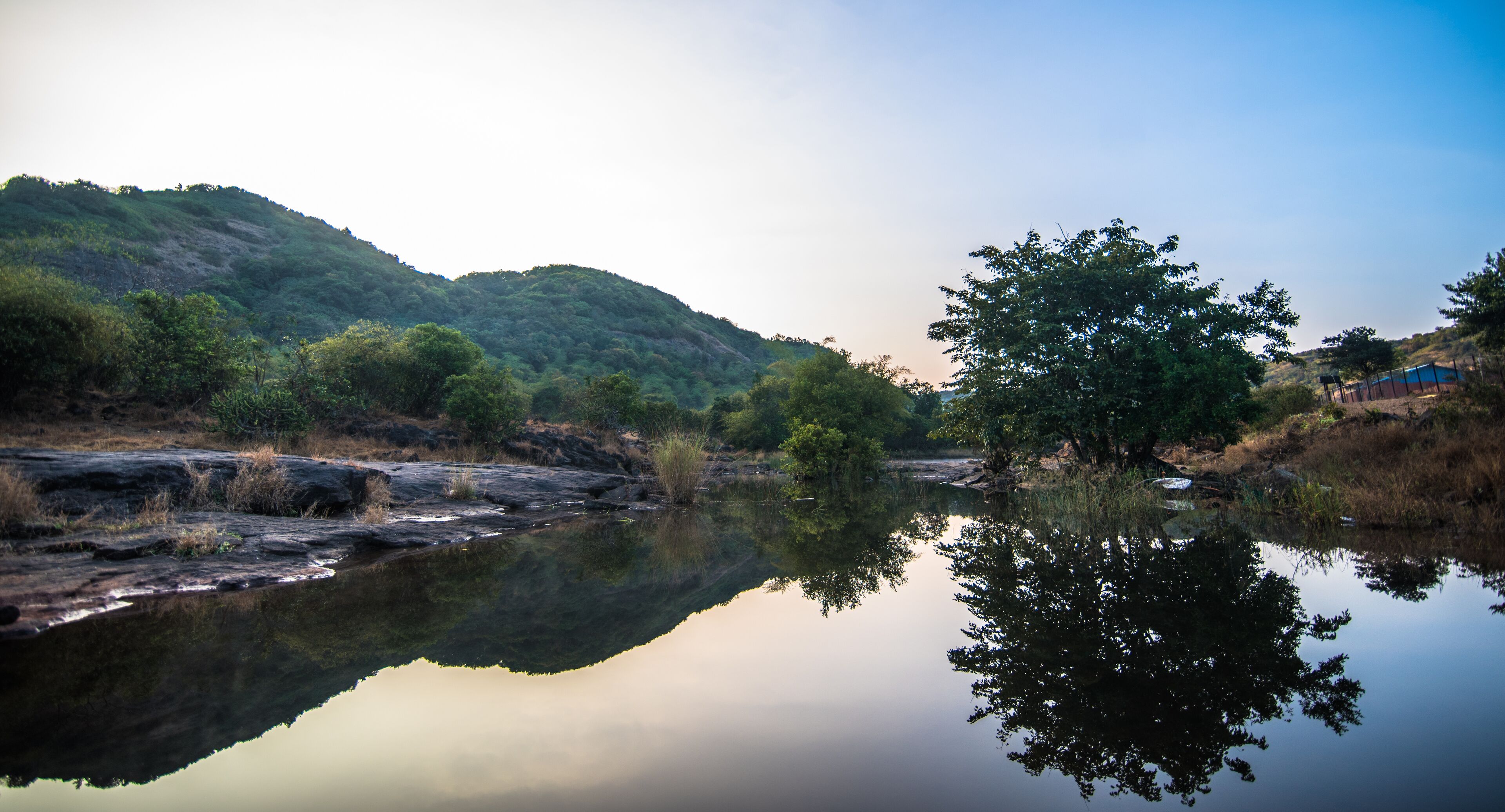 A calm river reflecting trees and hills.
