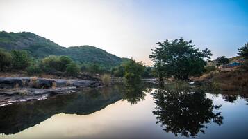 A calm river reflecting trees and hills.
