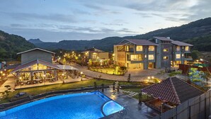 A hotel with multiple buildings, a swimming pool, and outdoor seating areas. - Mastiff Grand La Villae Resort (Mawal)