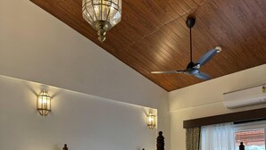 A four-poster bed with a wooden frame, two bedside tables, a ceiling fan, and two wall-mounted light fixtures. - Mastiff Grand La Villae Resort (Mawal)