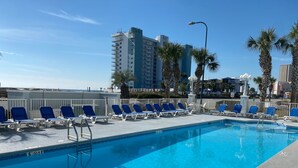 A pool area with blue lounge chairs and a clear blue pool. - Grand Caribbean 205 - Condo has beautiful views of the Gulf and great rates! (Orange Beach)
