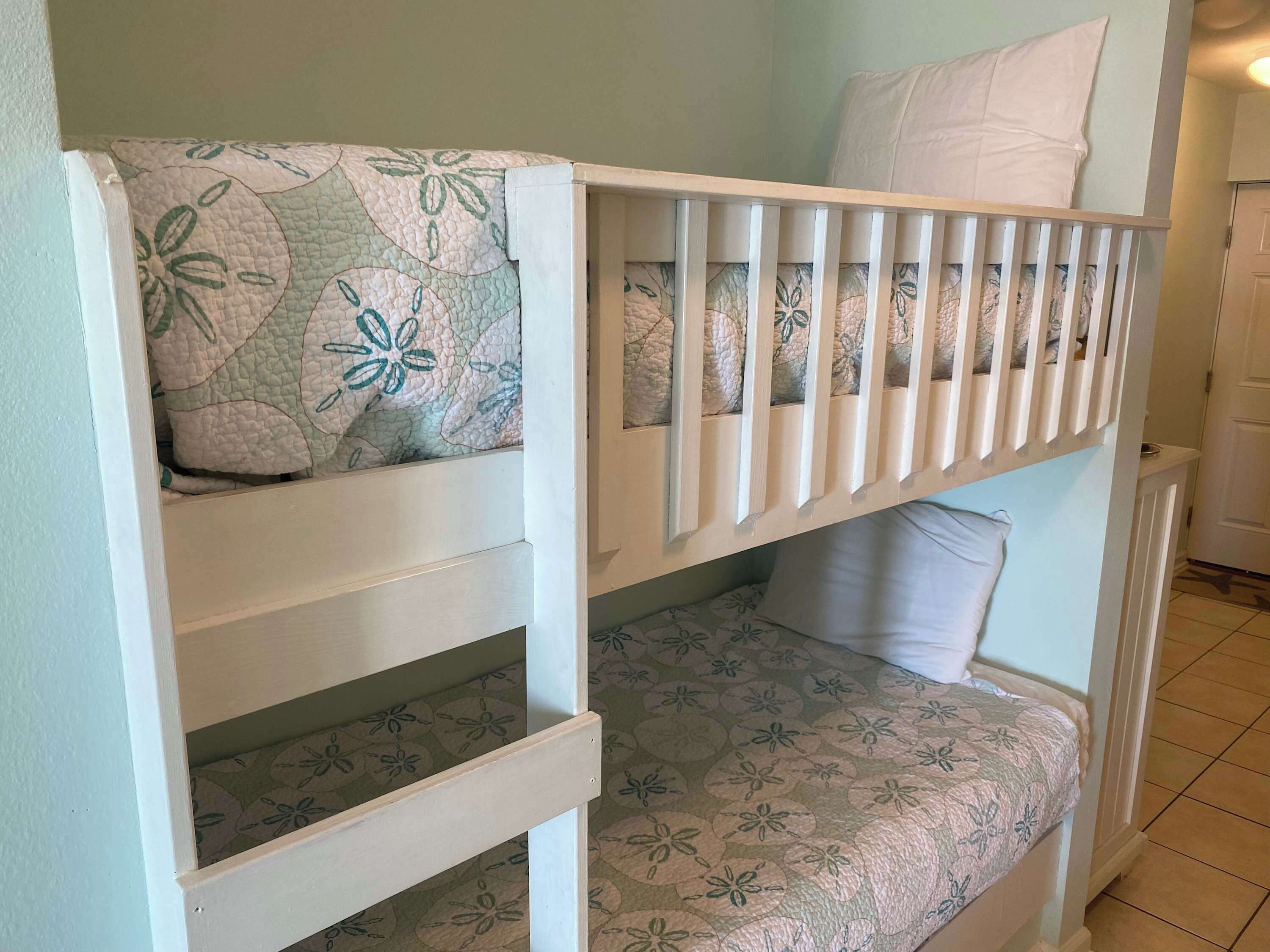 A bunk bed with floral-patterned bedding and a white headboard.