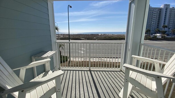 A balcony with white railings and a view of a parking lot and distant buildings. - Grand Caribbean 205 - Condo has beautiful views of the Gulf and great rates! (Orange Beach)