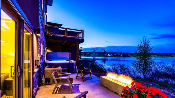 Un patio exterior con un jacuzzi, zona de estar y una chimenea.
