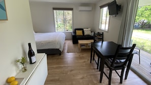 Una habitación moderna con una cama, un sofá, una mesa de comedor y un televisor.