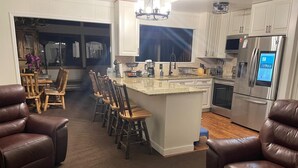 A modern kitchen with white cabinets, stainless steel appliances, and a central island with bar stools. - Relaxing Rustic ranch at Locust Lake!  with beautiful views!  Close to the Lake! (Pocono Lake)