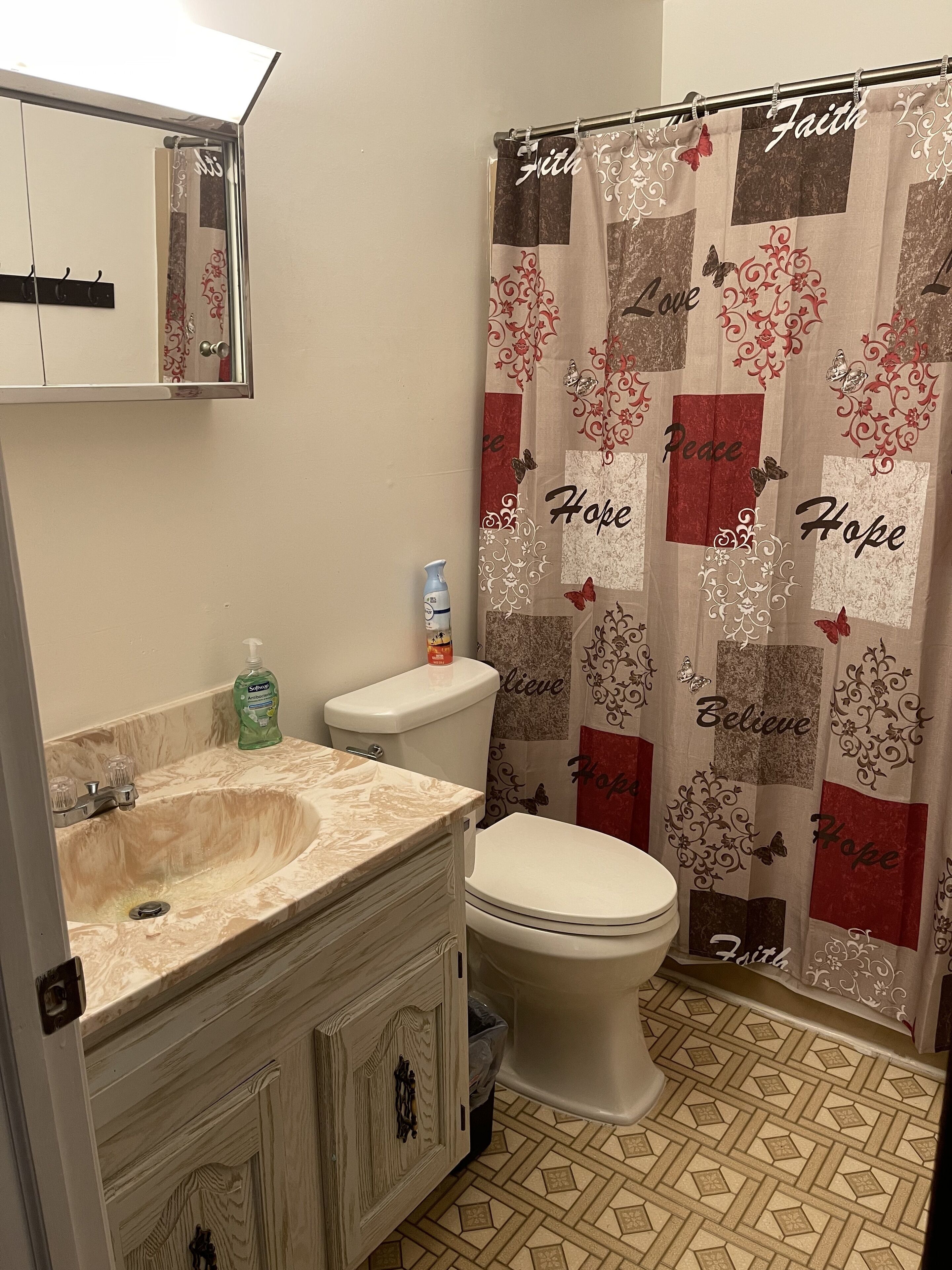 Baño con lavamanos, inodoro y cortina de ducha con frases motivacionales.