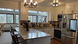 A modern kitchen with white cabinets, a large island, stainless steel appliances, and a chandelier. - Relaxing Rustic ranch at Locust Lake!  with beautiful views!  Close to the Lake! (Pocono Lake)