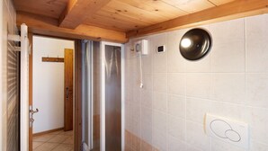 Ein Badezimmer mit Holzboden, einer Duschkabine und einem wandmontierten Waschbecken.
