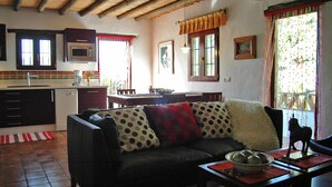 A cozy living room with a sofa, a dining table, and a kitchen area with a microwave. - Frigiliana 010 (Frigiliana)