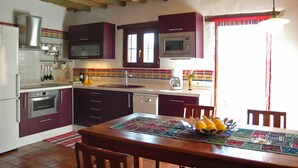 A kitchen with a dining table, a microwave, and a dishwasher. - Frigiliana 010 (Frigiliana)