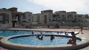 En swimmingpool med folk i, omgiven av byggnader med balkonger.