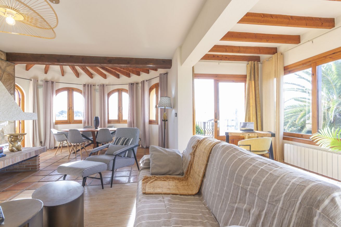 A spacious living area with a sofa, chairs, a dining table, and a laptop on a balcony.