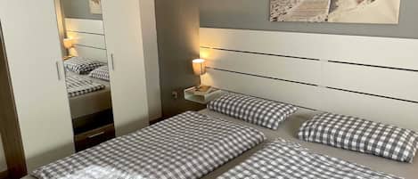 A hotel room with a bed, a nightstand, a lamp, a mirror, and a beach-themed wall art.