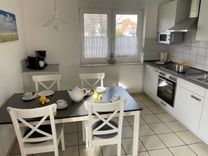A kitchen with white cabinets, a stove, a microwave, and a dining table with chairs.