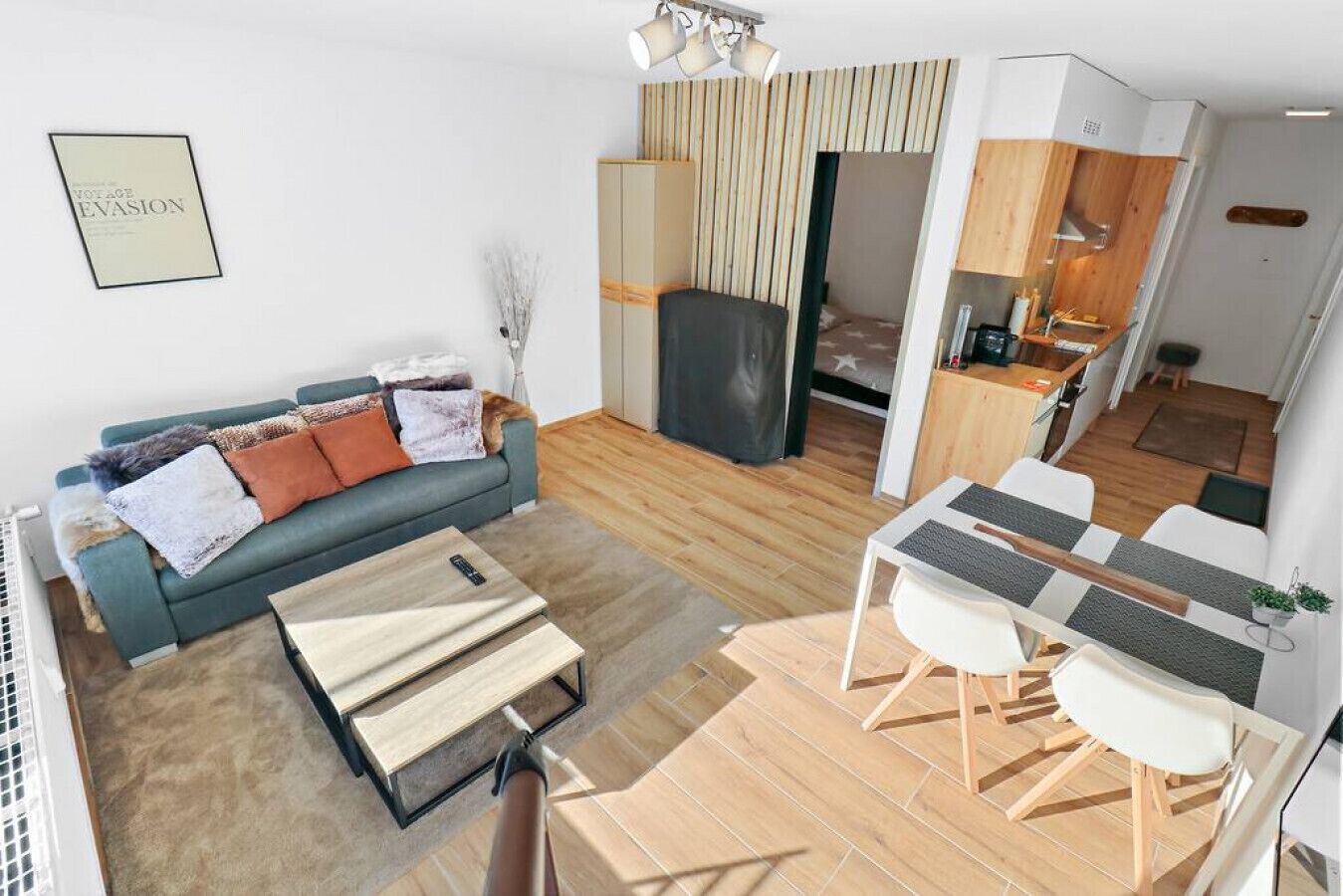 Un espacio habitable compacto con sofá, mesa de comedor y kitchenette.