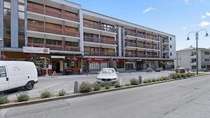 A multi-story hotel with balconies, a restaurant, and a parking area. - Cosy, renovated apartment in the heart of the resort (Crans-Montana)