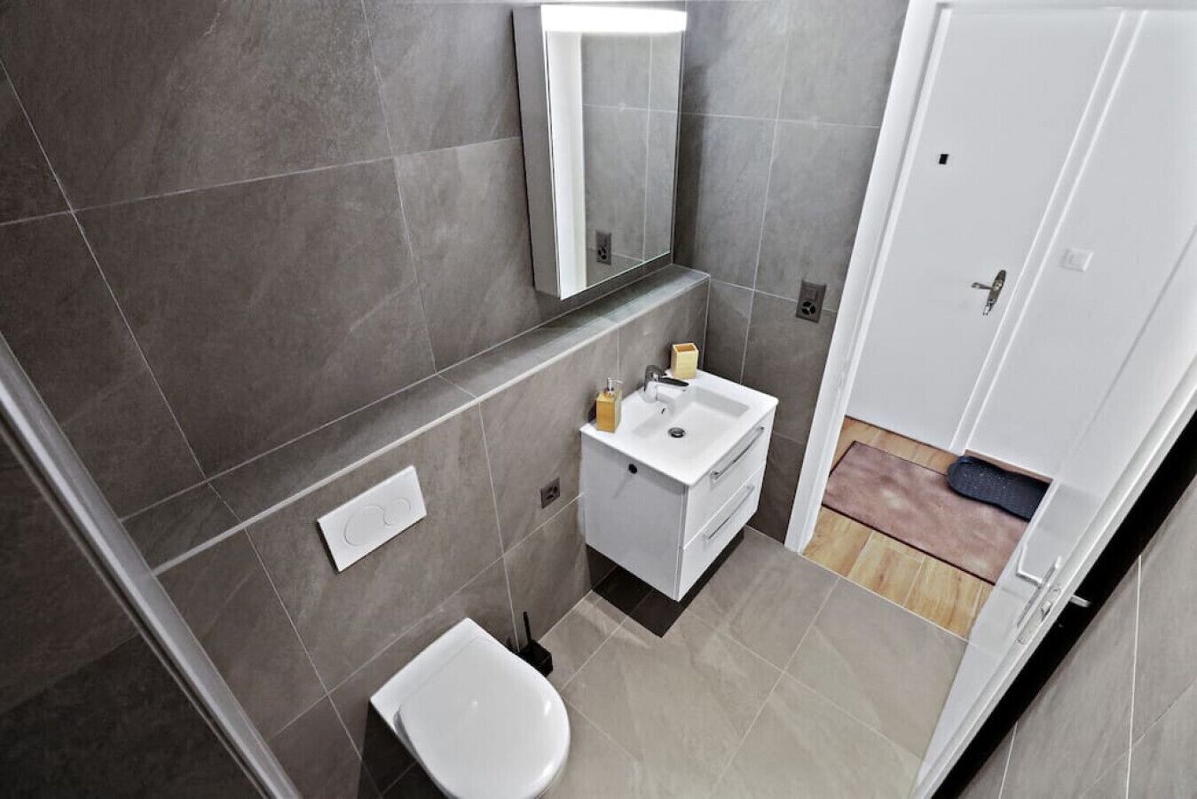 A compact bathroom with a toilet, sink, and mirror.