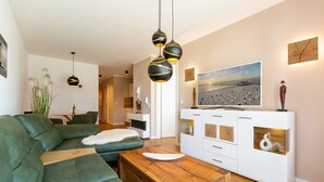 Una sala de estar moderna con un sofá verde, una mesa de centro de madera y un mueble de entretenimiento blanco con un televisor.