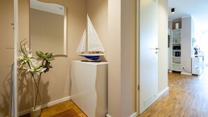 Un pasillo con un armario blanco, un modelo de velero pequeño y una planta en maceta.