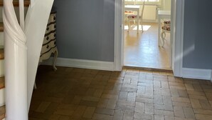 A staircase with white railings leading to a room with a gray wall and a door opening to a bright room with a table and chairs.