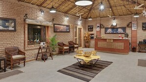 A rustic interior with brick walls, wooden furniture, and a thatched roof.