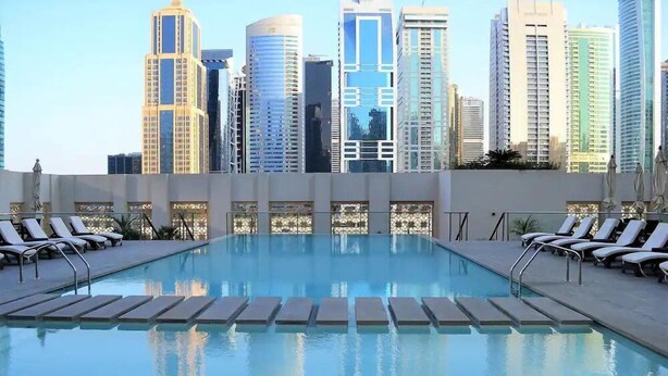 Piscina en la azotea con sillones y un horizonte urbano de fondo.