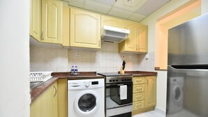 Cocina compacta con lavadora, horno y refrigerador de acero inoxidable.