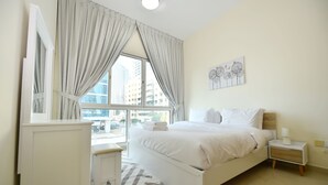 Un dormitorio con cama, mesita de noche y ventana con cortinas.