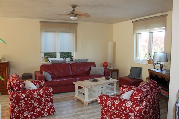 A living room with a red sofa, matching armchairs, a coffee table, and a ceiling fan. - The orchard house (Saint-Jean-Saverne)