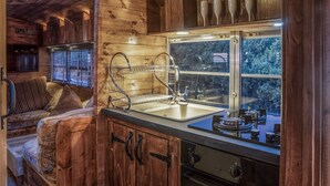 A wooden interior with a sink, window, and wooden cabinets. - American School Bus - Blossom Farm (Haverfordwest)