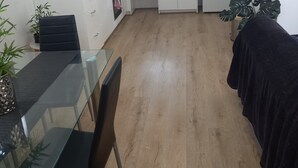 Eine kompakte Küche mit weißen Schränken, einer Mikrowelle, einem Kühlschrank und einem Essbereich mit einem Glastisch und Stühlen.